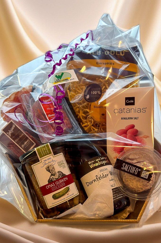 Geschenkkorb mit Gourmet-Lebensmitteln, Schokolade, Sekt und Wurstwaren.