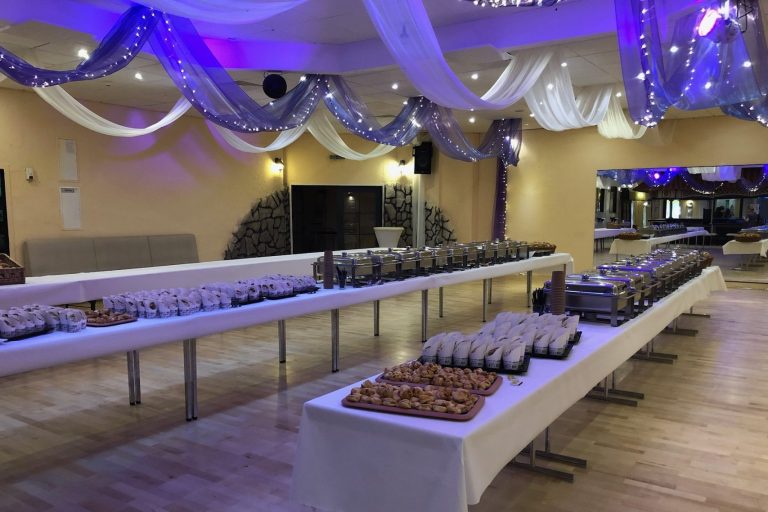 Festlich dekorierter Raum mit Buffets und platzierten Speisen auf langen Tischen.