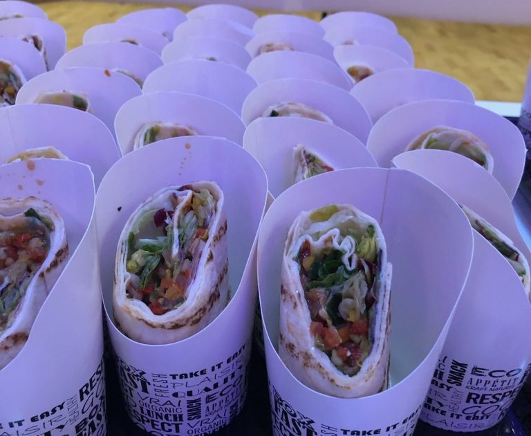 Mehrere gefüllte Wraps in weißen Faltverpackungen, übereinander angeordnet.