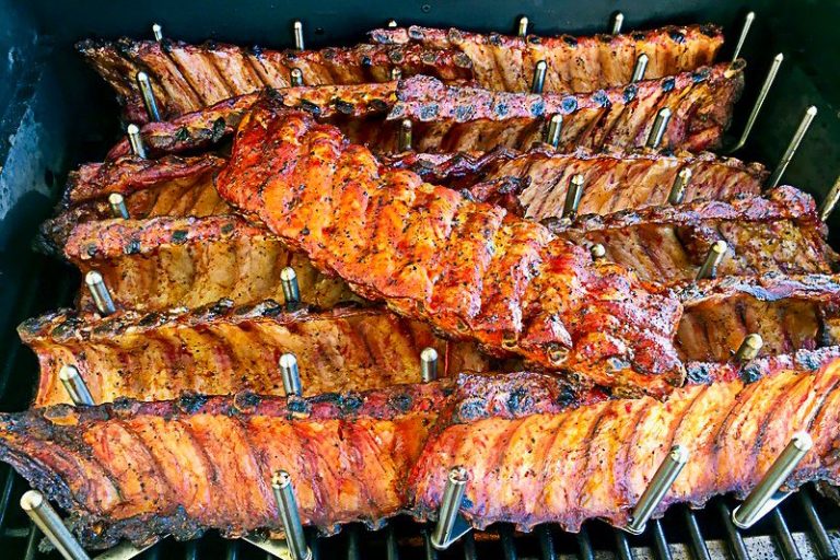 Gegrillte Rippchen, schön braun und karamellisiert, auf einem Grillrost angeordnet.