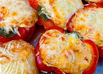 Gefüllte Paprika mit Käse überbacken, serviert auf einem Blech.
