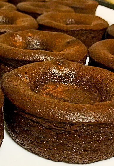 Braune, runde Kuchenformen mit einer Vertiefung in der Mitte, auf einem Teller angeordnet.