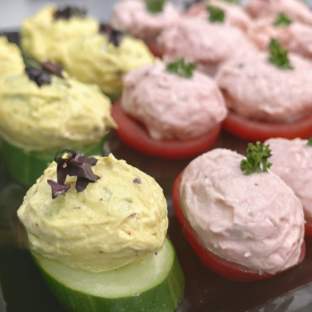 Bunte Häppchen aus Gurke, Tomate und verschiedenen Cremes, garniert mit Kräutern.