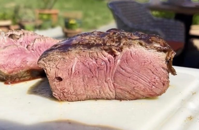 Saftiges, rosa gegartes Rindersteak auf einem Schneidebrett.