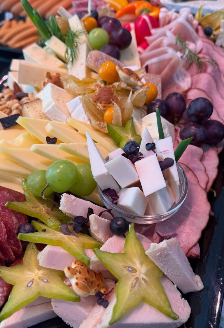 Bunte Platte mit Käse, Aufschnitt, Trauben, Sternfrucht und trockenen Früchten.