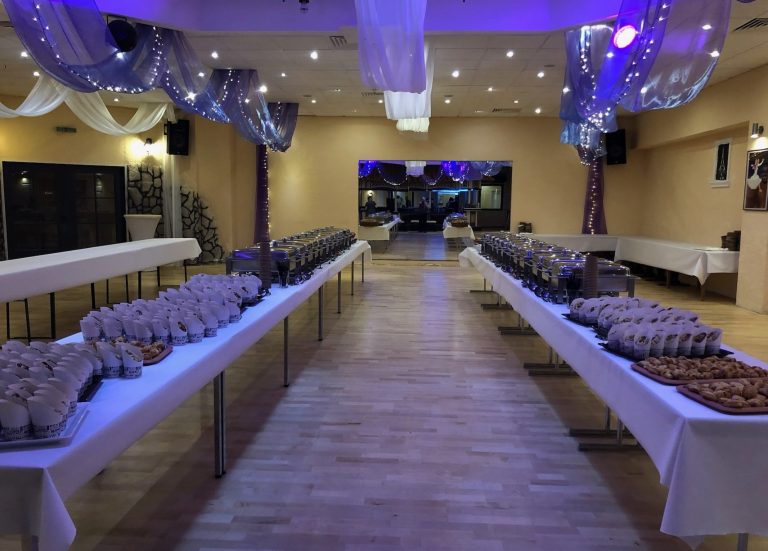 Langgestreckter Veranstaltungsraum mit festlich gedeckten Tischen und Buffet.