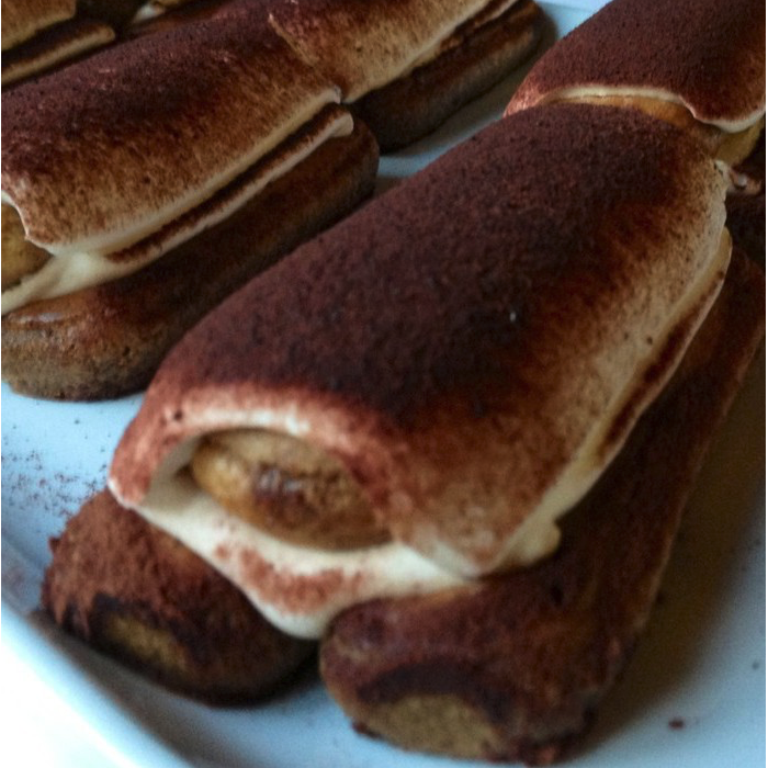 Leckere Tiramisu-Röllchen mit Schichten aus Keks und Creme, bestreut mit Kakaopulver.