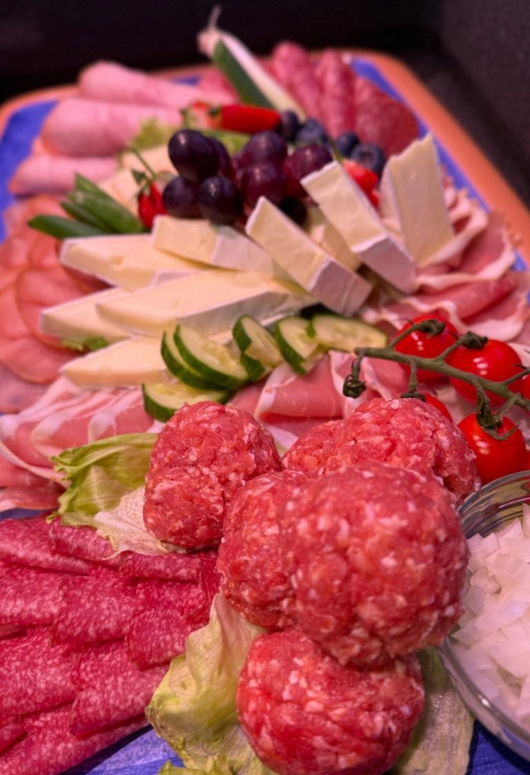 Ein farbenfrohes Kalteplatten -Arrangement mit Wurst, Käse, Trauben und Gemüse.